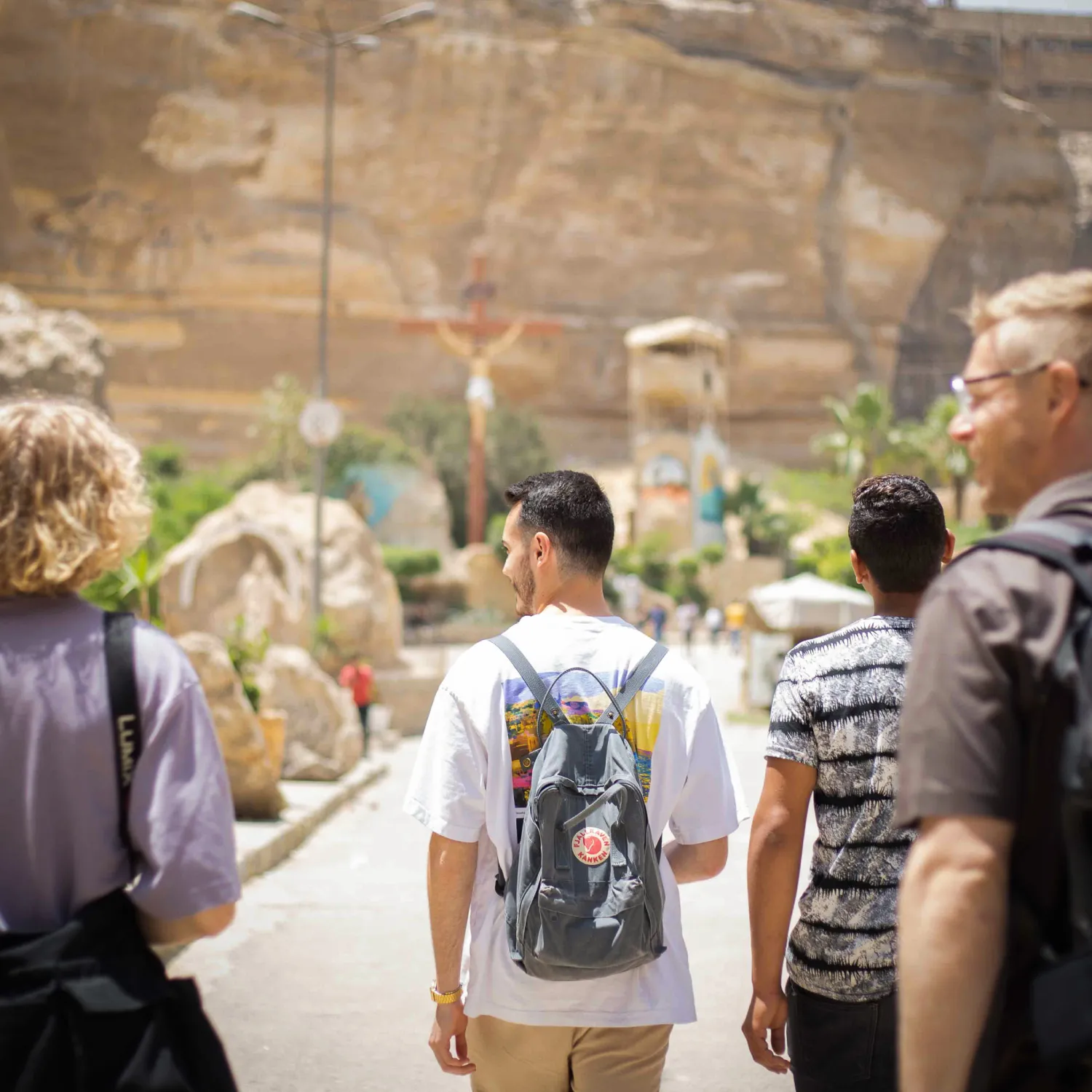 An image of a group of students with backpacks walking on a pathway towards a rocky mountain.